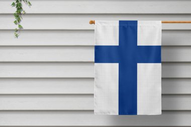 Finland national small flag hangs from a picket fence along the wooden wall in a rural town. Independence day concept. clipart
