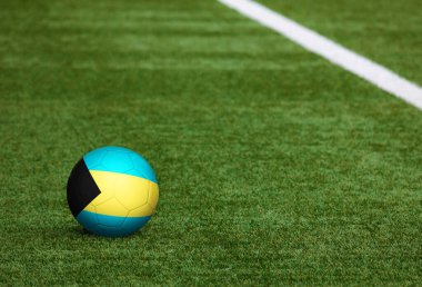 Futbol sahasında top Bahamalar 'ın bayraklarında. Ulusal futbol teması yeşil çimlerde. Spor yarışması konsepti.
