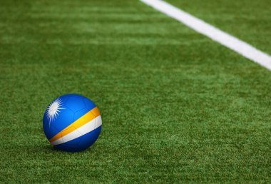 Marshall Adaları futbol sahasında top üzerinde bayrak. Ulusal futbol teması yeşil çimlerde. Spor yarışması konsepti.