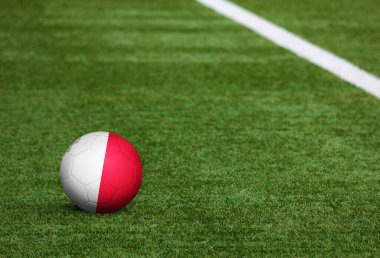Futbol sahasında top Malta bayrağında. Ulusal futbol teması yeşil çimlerde. Spor yarışması konsepti.