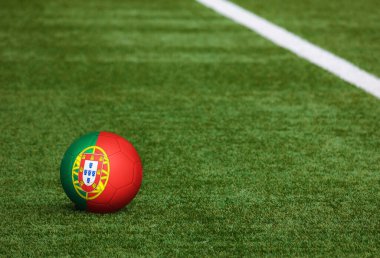 Futbol sahasında top Portekiz bayrağında. Ulusal futbol teması yeşil çimlerde. Spor yarışması konsepti.