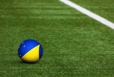Futbol sahasında top üzerinde Tokelau bayrağı. Ulusal futbol teması yeşil çimlerde. Spor yarışması konsepti.