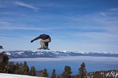 A snowboarder jumps over mountains and Lake Tahoe, California. clipart