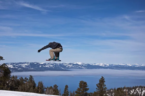 Dağlar ve Lake Tahoe, Kaliforniya üzerinde bir snowboard atlar.