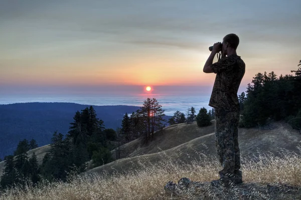 若い男夕暮れの山々 の眺めとカリフォルニア州メンドシーノ郡海岸の草が茂った斜面を調査します ストックフォト