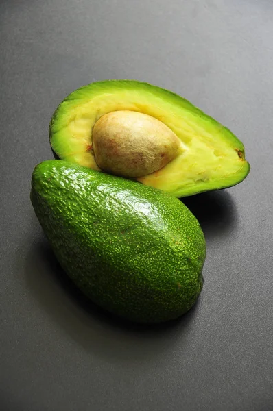Karanlık Bir Arka Plan Üzerinde Tek Yeşil Avokado Yarısı Yalan — Stok fotoğraf