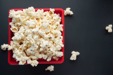 Beyaz ve siyah arka plan üzerinde kırmızı bir kap içinde patlamış mısır. Film için aperatifler.