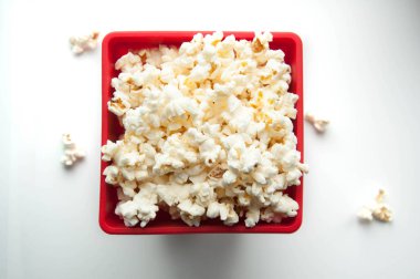 Beyaz ve siyah arka plan üzerinde kırmızı bir kap içinde patlamış mısır. Film için aperatifler.