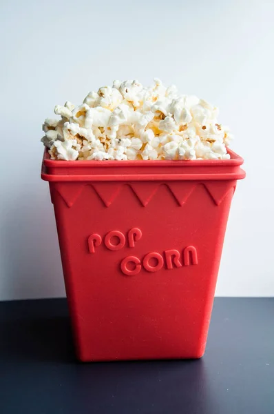 Popcorn in a red container on a white and black background. Snacks for the film.