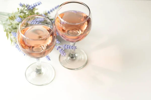 Transparent glass of wine. Pink wine. Festive mood. Alcohol for a group of friends. Delicious drink. Light background. Noble drink. Lavender and rose wine. Wine from lavender