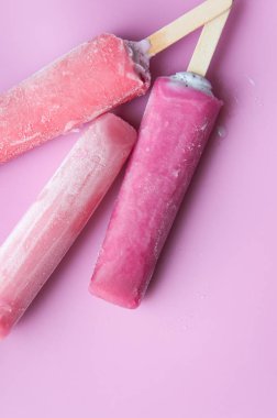 Pembe bir arka plan üzerinde bir sopa üzerinde parlak meyve dondurma. Donmuş meyve buzu. Yaz havası. Sıcak havalarda tatlı soğutma. Çocuklar için en sevdiği lezzet. Ev yapımı ahududu, çilek, karpuz buz