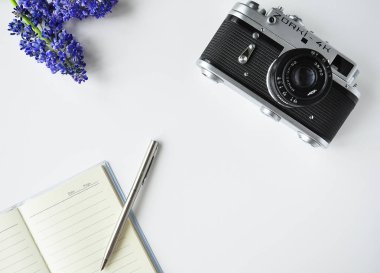 Site için Parlak İlginç arka plan tablosu. Masadaki ayrıntılar: Not defteri, kalem, kamera, çiçekler. Arka plan gezgini ve fotoğrafçı.