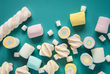 Mavi bir arka plan üzerinde doğal marshmallow tatlılar. Masaya serpiştirilmiş havadar çok renkli marshmallowlar.