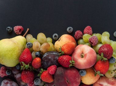 Vitamin meyve ve çilek doğal ürünlerdir. Armut, elma, erik, üzüm, çilek, ahududu, yaban mersini, siyah arka plan üzerinde şeftali. Doğal vitamin ler ve mineraller. Vegan eko gıda.