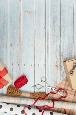 Hediye paketi. Kutular, kurdeleler, hediye kağıtları, halatlar, makas, fiyonklar, ahşap bir arka planda çiçekler. Sevgililer günü, doğum günü, anneler günü hediyeleri. Hediye paketine hazırlanılıyor.