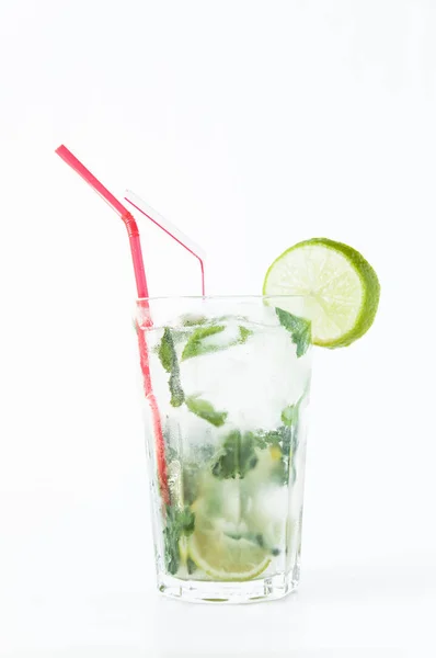 Mojito cocktail i genomskinligt glas med is. Recept på exotiska drinkar med mynta, lime och vit Rom. Glas med en cocktail på en vit bakgrund i solens strålar. — Stockfoto