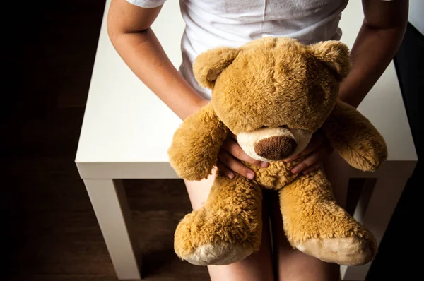 Küçük üzgün bir kız elinde oyuncakla oturuyor. Çocuk yetiştirmekle ilgili sorunlar. Çocuk barınakları. Yalnız ve terk edilmiş çocuklar..