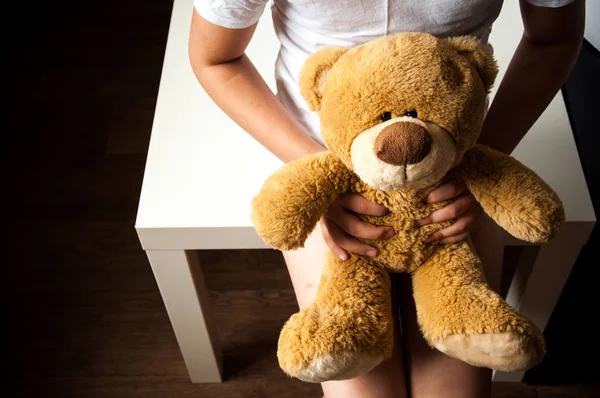 Küçük üzgün bir kız elinde oyuncakla oturuyor. Çocuk yetiştirmekle ilgili sorunlar. Çocuk barınakları. Yalnız ve terk edilmiş çocuklar..