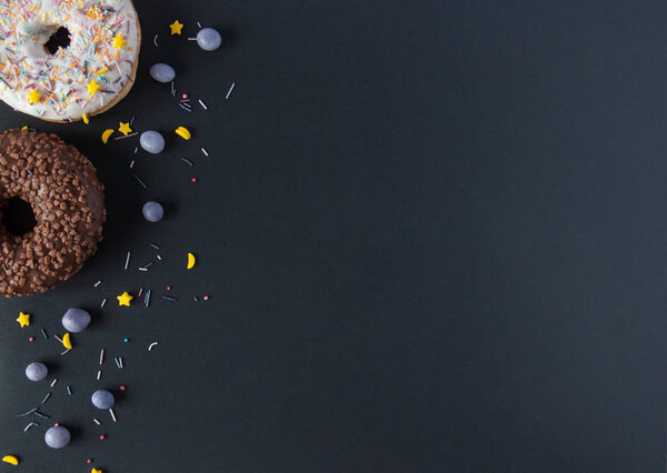 Сладкие пончики на черном фоне с шоколадом и ягодами
.