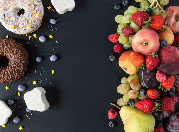 Много натуральных и здоровых витаминов фрукты, ягоды против сладкой и нездоровой пищи на черном фоне. Веганская экологически безопасная еда. Правильные продукты для потери веса и неправильные продукты для набора веса. Выбор:
