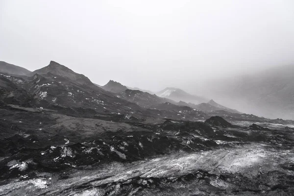 Solheimajokull Glacier in Iceland showing ash piles on the ice and heavy fog.