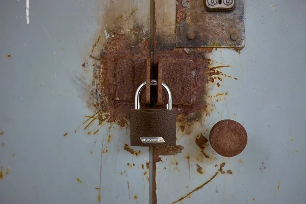 Cerradura marrón en puerta de hierro gris oxidado Fotos de stock