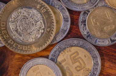 $5 ve $10 peso iyi ekonomi düşündüren ahşap bir tablodaki diğer paralar ortasında Meksika sikkeleri