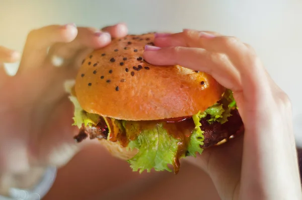 Marul ve siyah susam rustik bir restoranda lezzetli bir hamburger eliyle