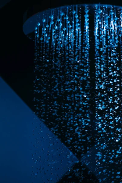 水の滴は青い光の中でシャワーに落ちることができます 水は閉まります 水の流れ 大きな丸い散水はシャワーで行うことができます — ストック写真