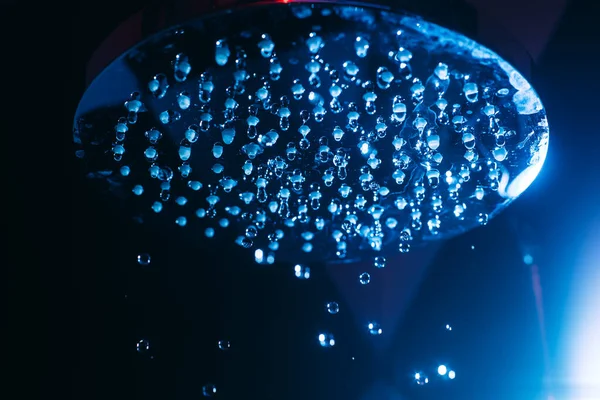 水の滴は青い光の中でシャワーに落ちることができます 水は閉まります 水の流れ 大きな丸い散水はマクロ写真 — ストック写真