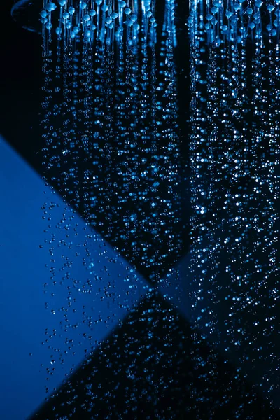 水の滴は青い光の中でシャワーに落ちることができます 水は閉まります 水の流れ 大きな丸い散水はマクロ写真 — ストック写真
