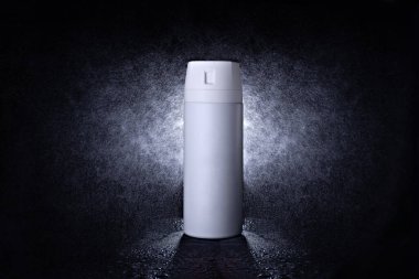 Siyah arka planda siyah metal bir teneke kutuda deodorant var. Terleme önleyici spreyin reklam fotoğrafı. Şişeyi su püskürterek hazırla..