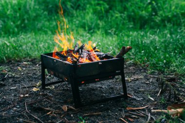 Yanan odunla doldurulmuş küçük, katlanabilir bir brazier. Izgarada yemek pişirmek. Doğada güvenli ateş.
