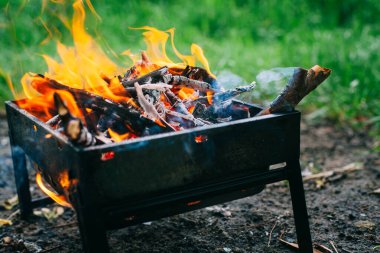 Yanan odunla doldurulmuş küçük, katlanabilir bir brazier. Izgarada yemek pişirmek. Doğada güvenli ateş.