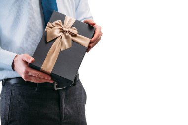 Bir adam elinde kahverengi bir kurdeleyle bir hediye tutuyor. Beyaz arka planda açık tişörtlü, kravatlı bir adam. Kara hediye kutusu ellerinde. Yazı için yer.