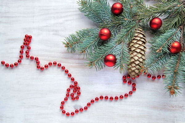 Beyaz ahşap zemin ve kırmızı topları bir şiş ile Noel ağacı dalı