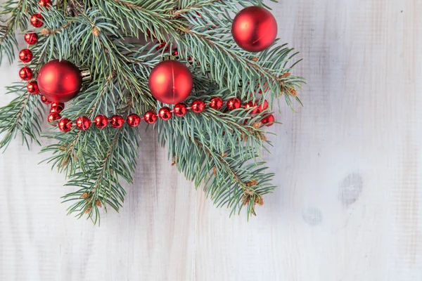 Beyaz ahşap zemin ve kırmızı topları bir şiş ile Noel ağacı dalı