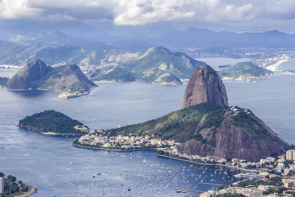 Views from Christ The Redeem mountain over Sugar Loaf, Rio do Janeiro city, suburbs and favelas, amazing views over the bays, islands, beach and the city skyline from the top on a cloudy day, Brazil