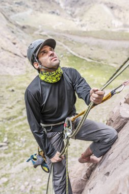 Santiago, Şili, merkezi Andes Dağları içinde tırmanma duvarı üzerinde ikinci dağcı güvenliğini sağlamak için yol kadar koyarak sonra ip ile çalışan bir adam dağcı tırmandı