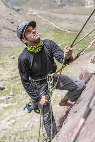 One man climber working  with the rope after putting up the route climbed in order to secure the second climber on a climbing wall inside central Andes mountains at Santiago, Chile