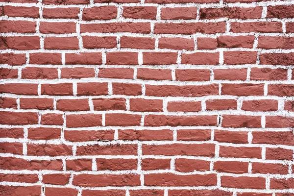 A red and white wall textured pattern of the bricks one over another fitting perfectly inside their space. Wall of a rural town on Chilean countryside, Cobquecura, Chile