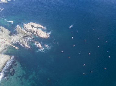 Güneşli bir günde kayalık kıyı ve deniz manzaralı tekneler. 