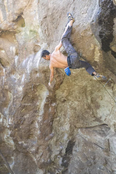 The last movements to reach the summit by a male climber. Rock climbing inside the Andes mountains at Cajon del Maipo, Chile. Climber solving the movements of \