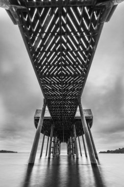 Llanquihue Gölü 'ndeki Frutillar kasabasının muhteşem manzarası. Yağmurlu bir sonbahar gününde uzun pozlama sahnesinde karamsar bir karamsar gökyüzü. Beton sütunlarıyla modern bir iskelenin harika dokuları.