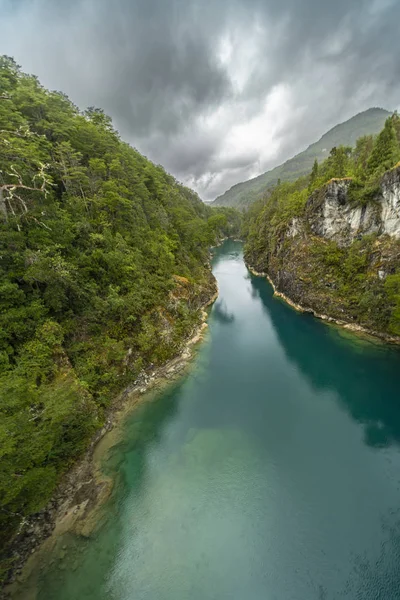 Kuzey Şili Patagonya 'daki dehşet verici köprü, Puelo nehri, dramatik bir gökyüzü altında engebeli engebeli doğa üzerindeki turkuvaz sularıyla dar boğazın etrafında dönüyor.