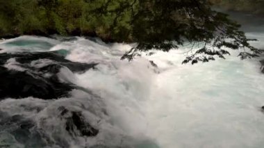 Caburgua Nehri 'nin vahşi beyaz suları Carileufu Şelalesi' ne dökülüp atlıyor. Pucon 'daki Şili yağmur ormanlarının güneyinde inanılmaz bir manzara, biraz dinlenmek için cennet manzarası.
