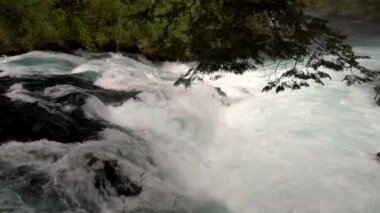 Caburgua Nehri 'nin vahşi beyaz suları Carileufu Şelalesi' ne dökülüp atlıyor. Pucon 'daki Şili yağmur ormanlarının güneyinde inanılmaz bir manzara, biraz dinlenmek için cennet manzarası.