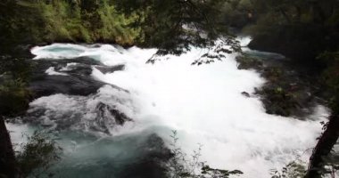 Caburgua Nehri 'nin vahşi beyaz suları Carileufu Şelalesi' ne dökülüp atlıyor. Pucon 'daki Şili yağmur ormanlarının güneyinde inanılmaz bir manzara, biraz dinlenmek için cennet manzarası.