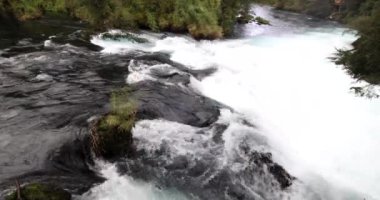 Caburgua Nehri 'nin vahşi beyaz suları Carileufu Şelalesi' ne dökülüp atlıyor. Pucon 'daki Şili yağmur ormanlarının güneyinde inanılmaz bir manzara, biraz dinlenmek için cennet manzarası.