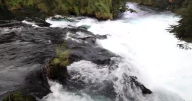 Caburgua Nehri 'nin vahşi beyaz suları Carileufu Şelalesi' ne dökülüp atlıyor. Pucon 'daki Şili yağmur ormanlarının güneyinde inanılmaz bir manzara, biraz dinlenmek için cennet manzarası.